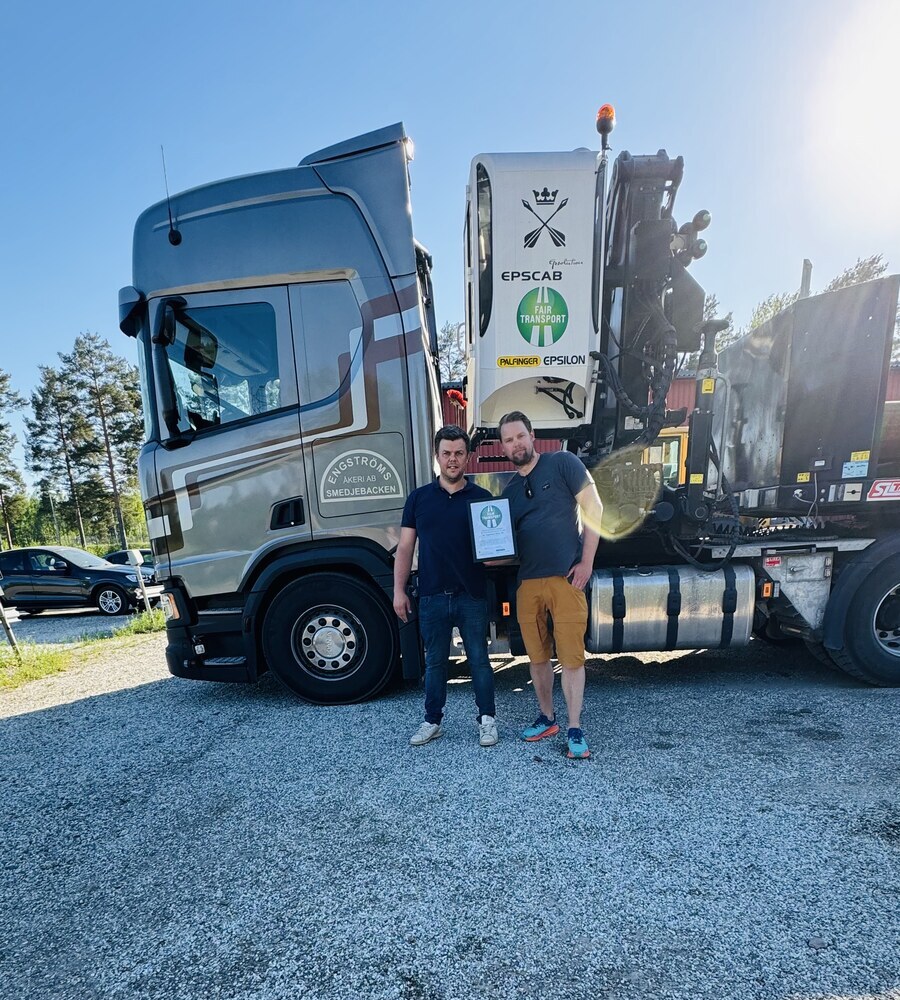 Magnus och Fredrik Engström med Fair Transport-diplomet framför en Scania timmerbil